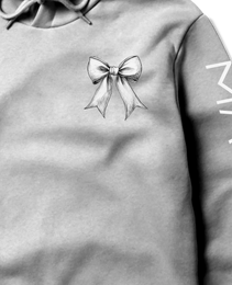 Gray cropped hoodie with a delicate bow design on the chest and ‘MAGICAL’ text printed on the sleeve.