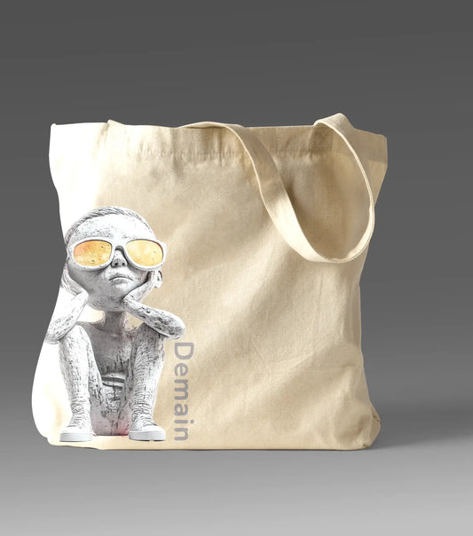 Demain Tote bag featuring a captivating design of a boy in sunglasses gazing upward, symbolizing hope, curiosity, and connection to the future, with ‘Demain’ text printed along the side.