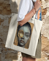 Golden Gaze Tote bag featuring an artistic design of a woman’s face with a captivating golden eye patch, symbolizing bold and expressive art.